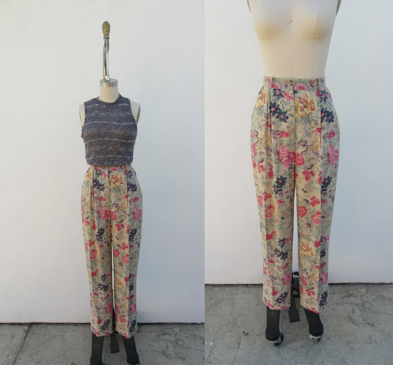 May include: High-waisted pants with a floral print in shades of pink, yellow, and blue on a beige background. The pants have a wide leg and are made of a lightweight fabric.