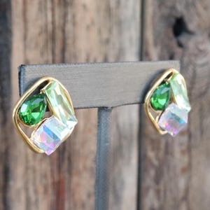 K&ouml;nnte beinhalten: Ein Paar goldfarbene Ohrringe mit gr&uuml;nen und schillernden Steinen. Die Ohrringe haben die Form eines Quadrats mit abgerundeten Ecken.