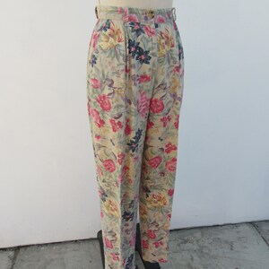 May include: Beige high-waisted pants with a floral print featuring pink, yellow, and blue flowers.