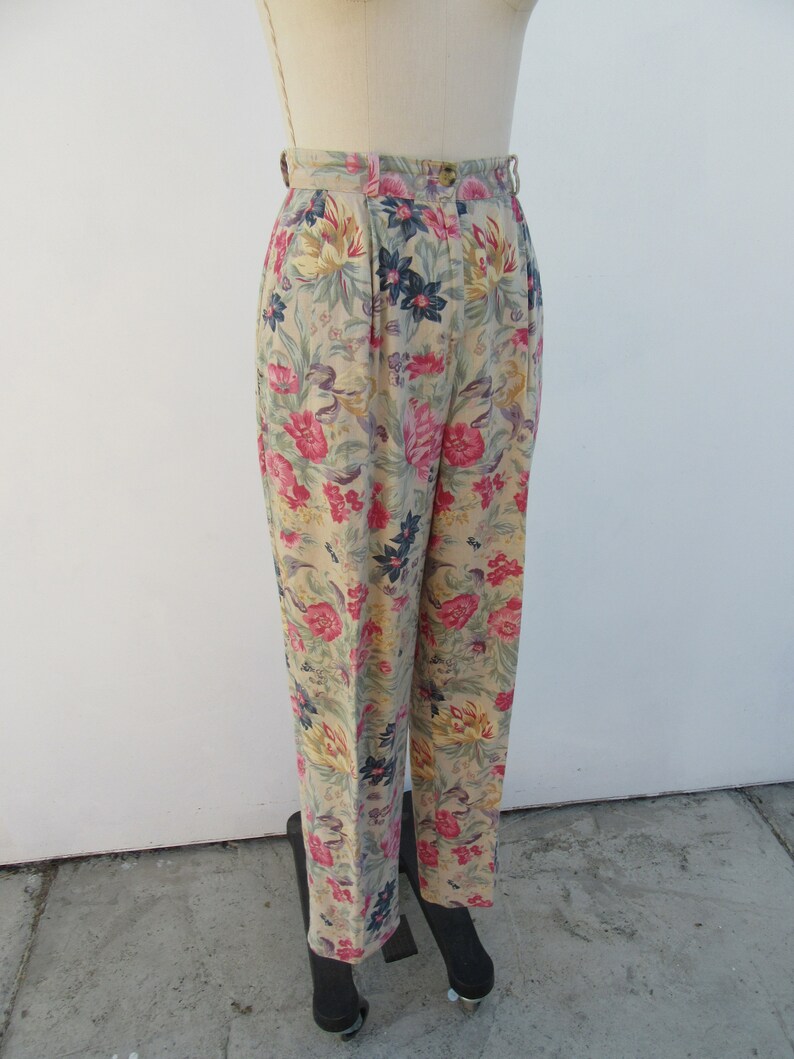May include: Beige high-waisted pants with a floral print featuring pink, yellow, and blue flowers.