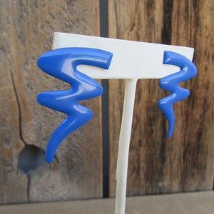 May include: A pair of blue abstract shaped earrings. The earrings are made of plastic and have a glossy finish.