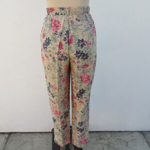 May include: Beige high-waisted pants with a floral print featuring pink, blue, and green flowers.