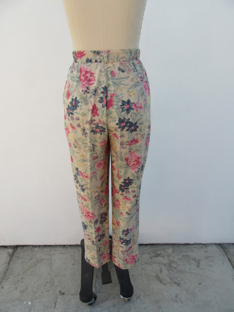 May include: Beige high-waisted pants with a floral print featuring pink, blue, and green flowers.
