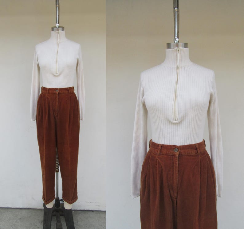 May include: A white ribbed turtleneck sweater with a zipper and brown corduroy pants.