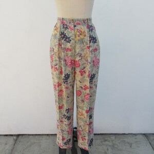 May include: High-waisted pants with a floral print in shades of pink, yellow, green, and blue. The pants have a pleated front and a straight leg.