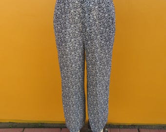 Puede incluir: Pantalón de cintura alta con estampado floral en tonos azules y blancos. El pantalón tiene pierna ancha y un corte holgado.