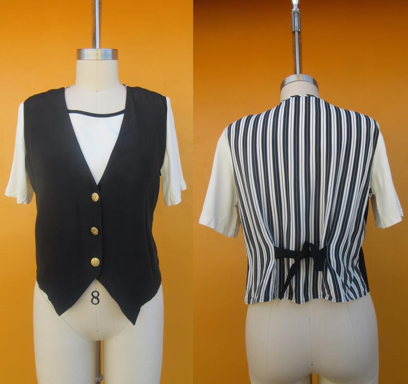 Peut inclure: Un gilet ray&eacute; noir et blanc avec un gilet en satin noir superpos&eacute;. Le gilet a une fermeture &agrave; boutons et une ourlet pointu.