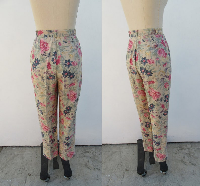 May include: Beige high-waisted pants with a floral print featuring pink, red, and blue flowers.