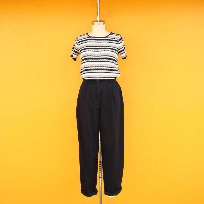 May include: A black and white striped short-sleeved shirt with a black pair of high-waisted trousers.