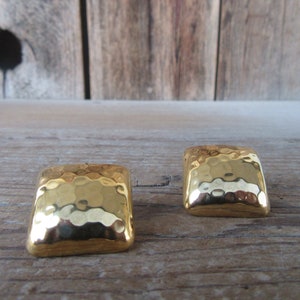 May include: A pair of gold-toned square earrings with a hammered texture.