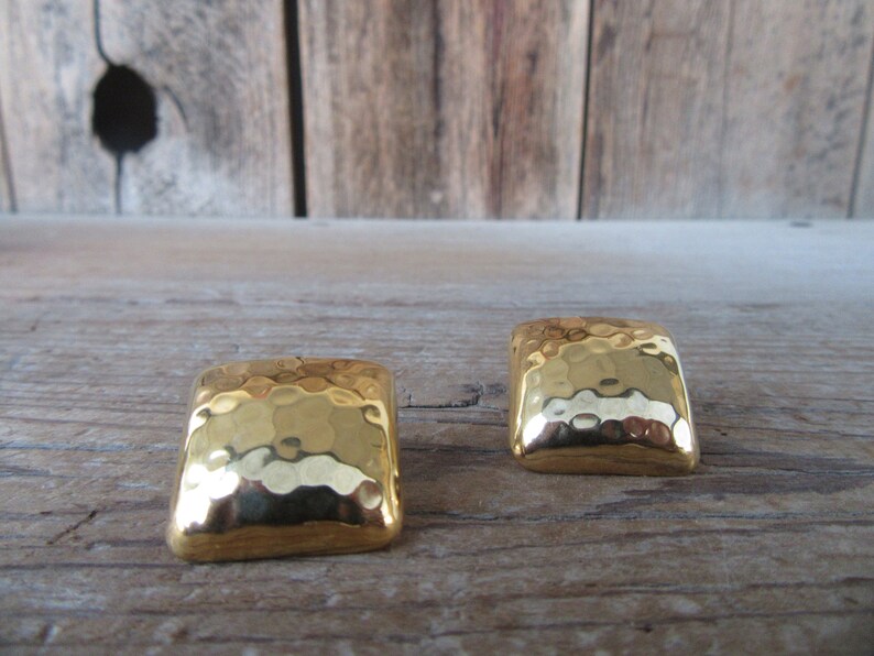 May include: A pair of gold-toned square earrings with a hammered texture.