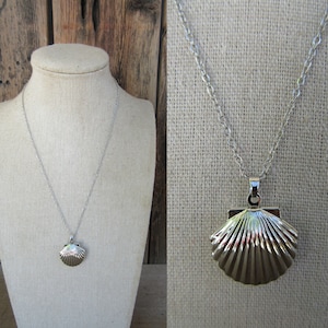 May include: A silver necklace with a seashell pendant. The pendant is detailed with ridges and has a shiny finish.