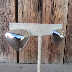 Può includere: Un paio di orecchini a forma di cuore color argento. Gli orecchini sono lisci e lucidi.