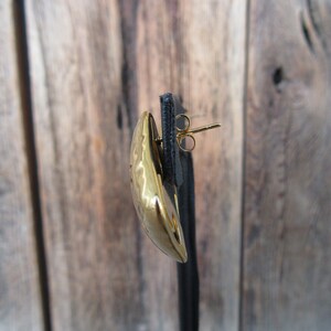 May include: A gold-toned earring with a hammered texture and a post back.