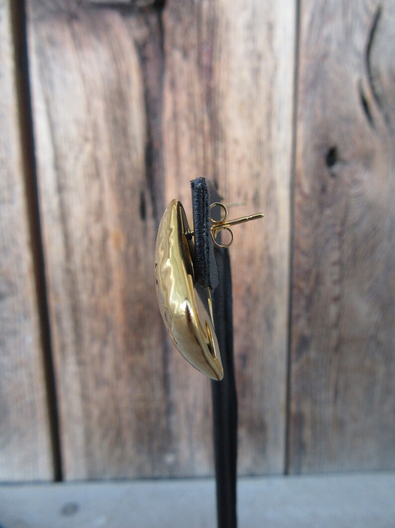 May include: A gold-toned earring with a hammered texture and a post back.