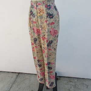 May include: High-waisted pants with a floral print featuring pink, yellow, blue, and green flowers on a beige background.
