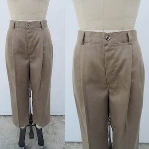 Puede incluir: Un pantalón marrón de pierna recta con un detalle de pliegue. El pantalón tiene cierre de botón y cremallera.