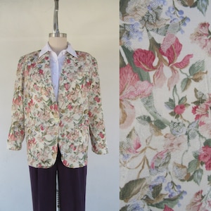 May include: A cream-colored blazer with a floral print featuring pink, red, and green flowers. The blazer has a button closure and long sleeves.