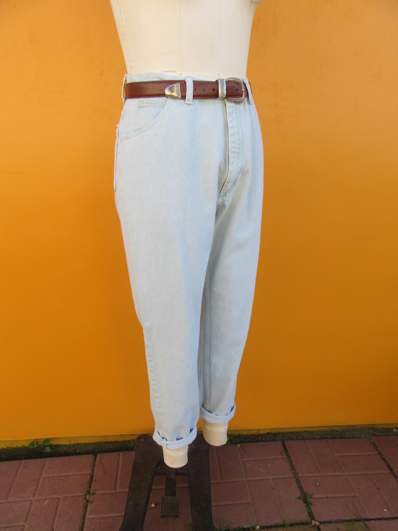 Op de afbeelding: Lichtblauwe denim jeans met een bruine leren riem. De jeans heeft een relaxte pasvorm en is aan de onderkant gecuffed.