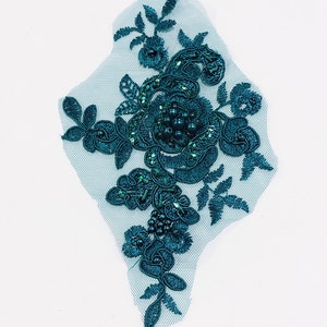 May include: Teal blue floral lace applique with beaded embellishments. The applique is on a sheer mesh fabric.