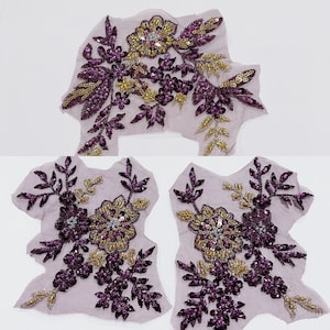 May include: Two purple and gold floral appliques with sequins and beads. The appliques are on a sheer fabric and are perfect for adding a touch of sparkle to any project.