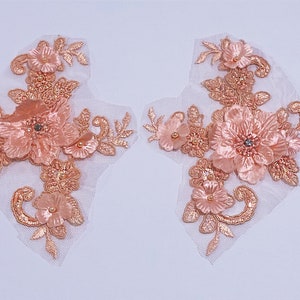 May include: Two peach-colored floral appliques with a delicate lace design and pearl accents. The appliques are perfect for adding a touch of elegance to clothing, accessories, or home decor.