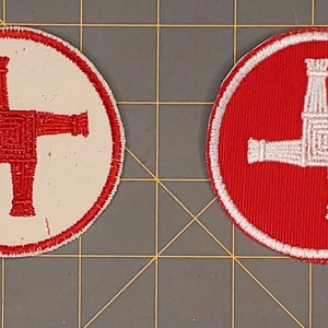 May include: Two round embroidered patches with a white Celtic cross on a red background and a red Celtic cross on a white background.