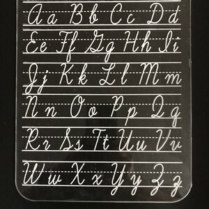 May include: A clear plastic cursive writing guide with the text "I CAN WRITE IN CURSIVE" at the top. The guide displays uppercase and lowercase cursive letters in white against a black background.