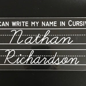 May include: A clear plastic nameplate with black lines and the text "I can write my name in cursive". The name "Nathan Richardson" is written in cursive on the nameplate.