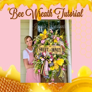 May include: A bee-themed wreath with a pink and black checkered ribbon, yellow and black striped ribbon, and a wooden sign that reads "Fresh and Local Sweet Honey Pure Organic Raw". The wreath is decorated with artificial flowers, greenery, and bees.