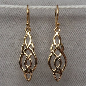 May include: A pair of gold Celtic knot dangle earrings. The earrings are made of a delicate, intricate design of interwoven knots.