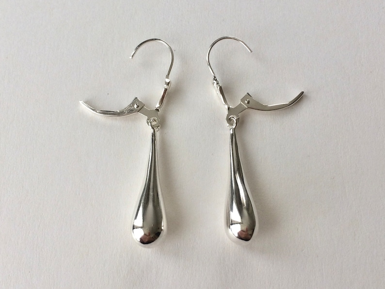 May include: A pair of silver teardrop dangle earrings with leverback closures.
