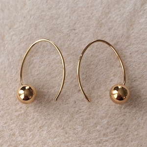 May include: A pair of gold hoop earrings with a small gold ball at the end of each hoop.