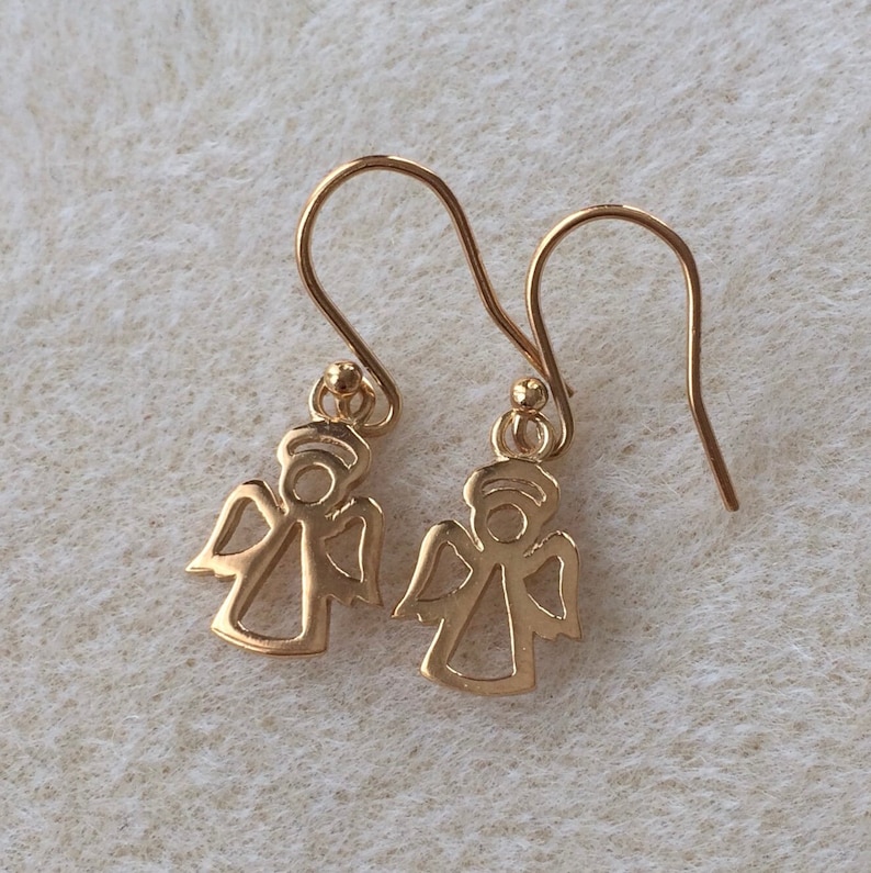 以下が含まれることがあります： シンプルなワイヤーフック留め具のついた、ゴールドの天使の形をしたドロップイヤリングのペアです。