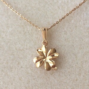 May include: A gold four-leaf clover pendant necklace. The pendant is detailed with a textured design and hangs from a delicate chain.