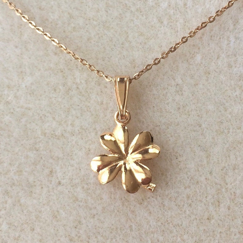 May include: A gold four-leaf clover pendant necklace. The pendant is detailed with a textured design and hangs from a delicate chain.