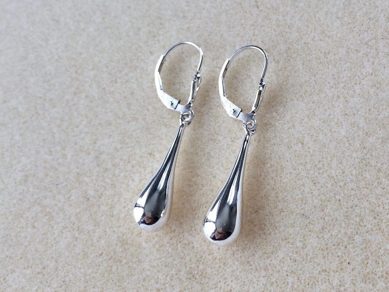 May include: A pair of silver teardrop dangle earrings with leverback closures.