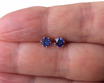 May include: A pair of silver stud earrings with small, round, blue gemstones.