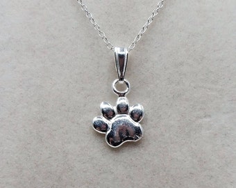 May include: A silver necklace with a small paw print charm.