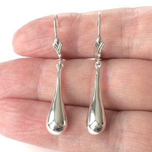 May include: A pair of silver teardrop dangle earrings with a simple, elegant design.