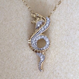 May include: A gold snake pendant necklace with clear sparkling stones. The snake is coiled and has a detailed design.