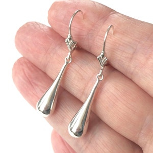 May include: A pair of silver teardrop dangle earrings with a delicate, twisted wire design at the top.