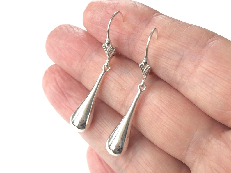 May include: A pair of silver teardrop dangle earrings with a delicate, twisted wire design at the top.