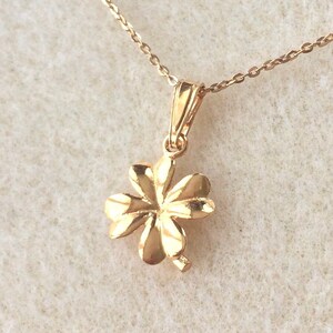 May include: A gold four-leaf clover pendant necklace. The pendant is detailed with a textured surface and hangs from a delicate gold chain.