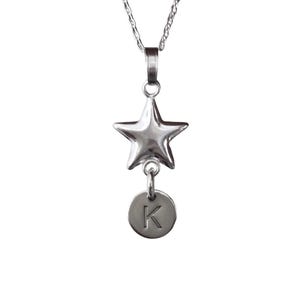 May include: A silver necklace featuring a star pendant and a small round charm with the letter 'K' engraved on it.