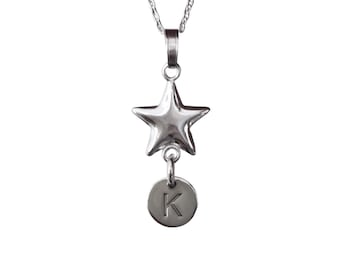 May include: A silver necklace with a star pendant and a small round charm with the letter 'K' engraved on it.