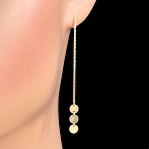 May include: Gold dangle earrings with three round charms hanging from a thin chain.