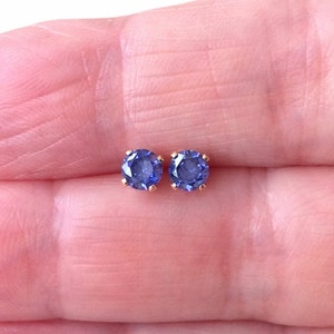 May include: A pair of small, round, purple gemstone earrings with gold settings.