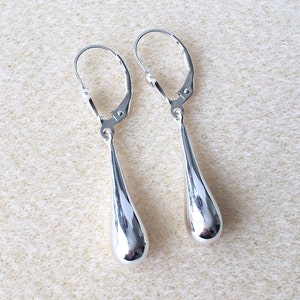 May include: A pair of silver teardrop dangle earrings with leverback closures.