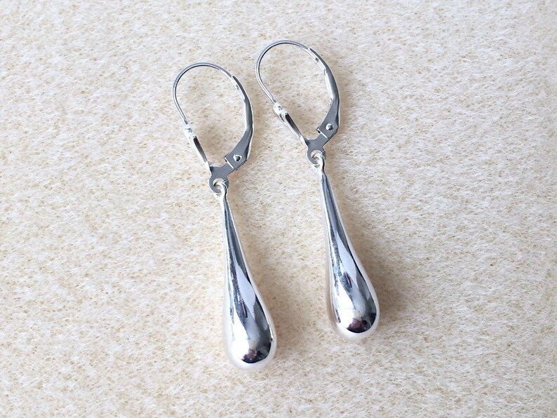 May include: A pair of silver teardrop dangle earrings with leverback closures.